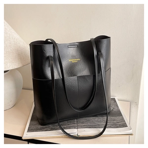 Detail of black tote bag with gold logo in a minimalist minimalist home setting