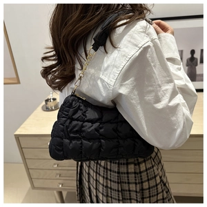 Gesteppte schwarze Wolken-Tasche mit Goldkette am Modell in minimalistischem Interieur