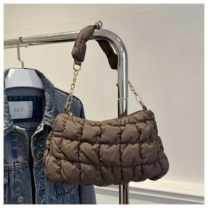 Nahaufnahme der braunen gesteppten Baguette-Tasche mit Goldkette und weicher Polsterung