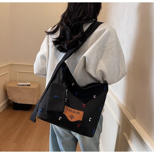 Detail view of large black canvas bucket bag with colorful embroidery and side coin purse