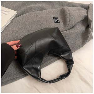 Detail of black geometric patchwork hobo bag made of premium matte leather with modern design