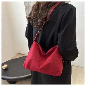Detailed view of red suede tote bag texture with adjustable strap and metal buckle