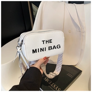 Detail of white camera bag with THE MINI BAG text and patterned jacquard strap