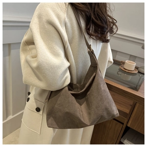 Detail of a dark brown hobo bag in soft suede fabric with an adjustable shoulder strap