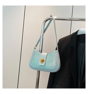 Détail du sac bandoulière à paillettes vert menthe avec fermoir rotatif doré sur blazer noir