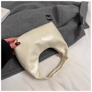 Detail of beige crescent shoulder bag with geometric patchwork on grey wool coat