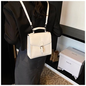 Close-up of cream vintage square backpack with metal horseshoe buckle and flap closure