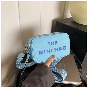 Close-up of light blue mini camera bag with textured leather and patterned wide strap