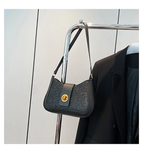 Détail du sac à bandoulière noir pailleté avec fermoir doré sur un cintre minimaliste