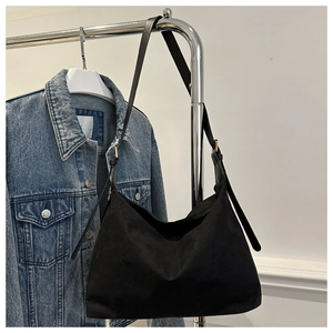 Detail of black suede hobo bag featuring adjustable leather strap and draped texture