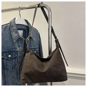 Detailed close-up of dark brown suede hobo bag with adjustable strap and metal buckle