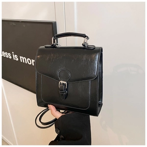 Close-up of black retro PU leather handbag with vintage buckle and textured finish