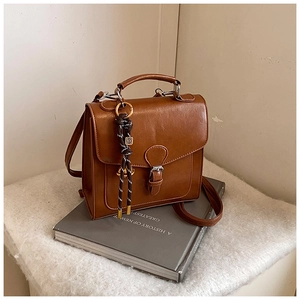 Detail of vintage brown leather satchel showing fine texture and woven pendant on books