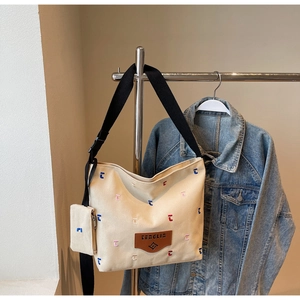 Detail of canvas bucket bag featuring colorful embroidery and small zipper coin purse