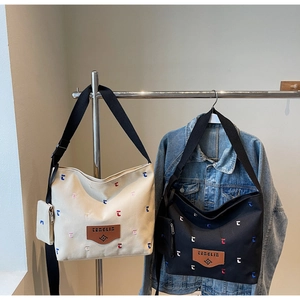 Detail view of canvas bucket bags with colorful embroidery, leather logo and small pouch
