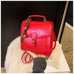 Detail of red vintage faux leather backpack with metallic buckle and bead tassel