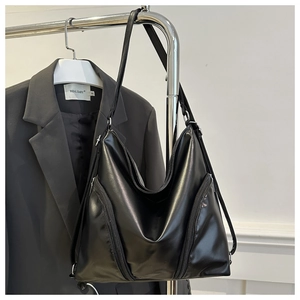 Detail of black large hobo bag with front zip pockets and smooth matte leather texture