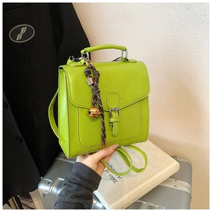 Detail of bright green retro mini backpack with metallic buckle and bell charm