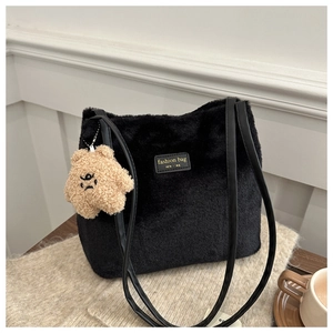Detail of black faux fur tote bag featuring a leather strap and a cute plush bear charm