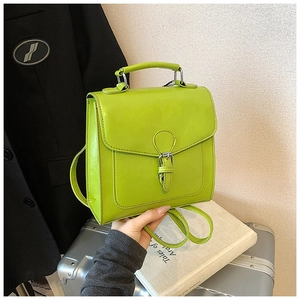 Detail shot of bright green faux leather small backpack with metal buckle on a suitcase