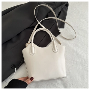 Close-up of minimalist beige bucket bag with fine stitching and golden hardware detail