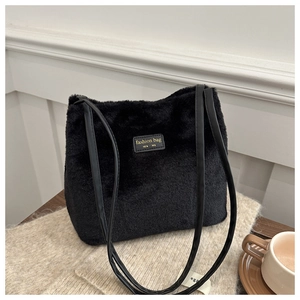 Detail of black faux fur tote bag with leather straps and gold NEW YORK logo patch