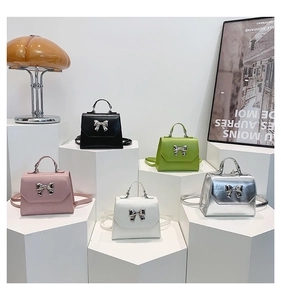 Detail of five stylish crossbody bags in various colors featuring silver metal bow accents