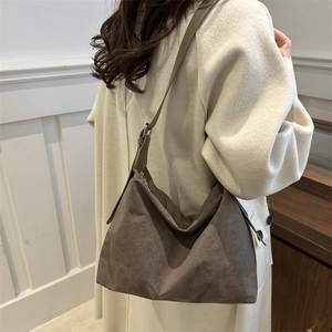 Retro brown nylon crossbody hobo bag with adjustable strap worn on beige coat