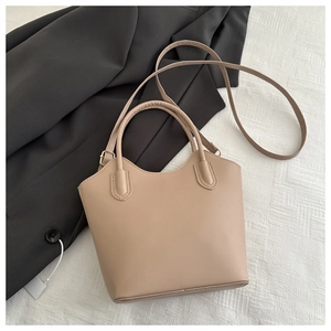 Detailed view of apricot minimalist bucket bag on black blazer with a long shoulder strap