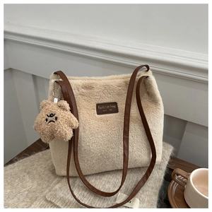 Close-up of beige faux fur tote bag with brown leather strap and cute teddy bear charm