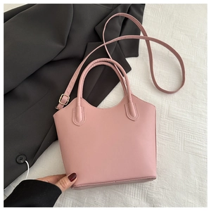 Detail of pink faux leather bucket bag with gold buckles on a blazer background
