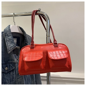 Detail of red faux-crocodile leather handbag with double front pockets and silver hardware