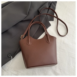Detail of dark brown leather bucket bag with top handles and adjustable gold metal buckle