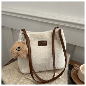 Detail of plush tote bag with faux fur texture, bear charm, and leather fashion tag