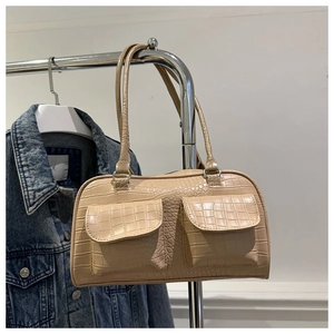 Detail of beige crocodile pattern handbag with front flap pockets and silver hardware