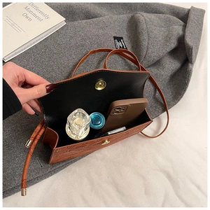 Détail intérieur du sac à main en cuir marron foncé avec téléphone et parfum