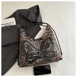 Close-up of leopard print tote bag with black butterfly applique and gold hardware details