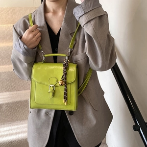 Bright green leather satchel with top handle and decorative bell charm on a model