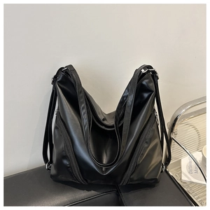 Detail of the soft black synthetic leather tote bag with stylish diagonal zippers