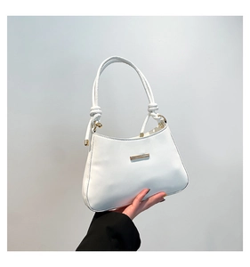 Close-up of white crescent bag showing knotted handle and gold metal fastener detail