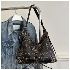 Detail of leopard print tote bag with black leather butterfly bow on denim background