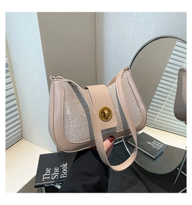 Detail of beige underarm bag with gold metallic clasp and textured fabric finish