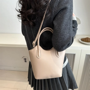 Minimalist beige leather bucket bag for women shown in a lifestyle indoor setting