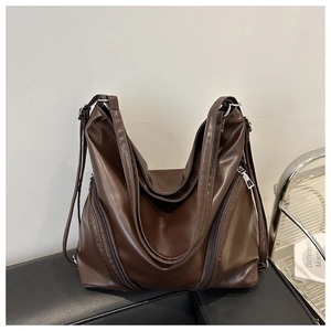 Detailed view of deep brown large tote bag with zipper accents on soft leather surface