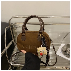 Detailansicht der Vintage-Handtasche aus braunem Wildleder mit Bärenanhänger und Bandverzierung