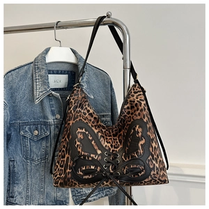 Detailed view of leopard print tote bag featuring a leather butterfly patch and lacing