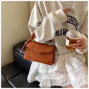 Détail du sac à main en cuir marron gaufré avec motif lotus et poignée nouée élégante