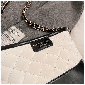Détail du sac matelassé crème avec bordure noire et bandoulière en chaîne dorée