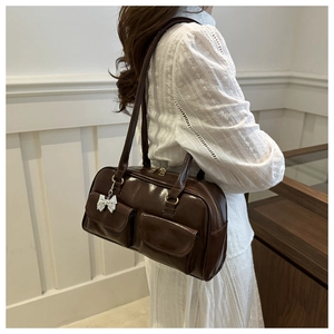 Detailed view of dark brown glossy shoulder bag with dual pockets and silver bow charm
