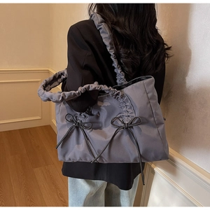 Detailed view of the cloud-shaped pleated handle and black bows on a blue-grey tote bag